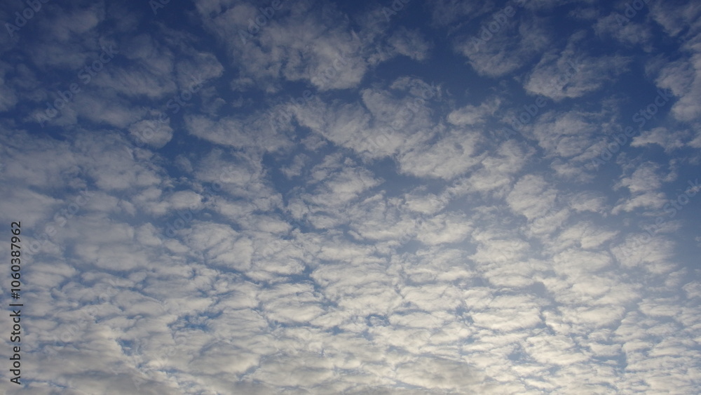 a sky filled with a pattern of small, fluffy clouds. These clouds are spread across the sky, creating a textured appearance a sky filled with a pattern of small, fluffy clouds. These clouds are spread across the sky, creating a textured appearance