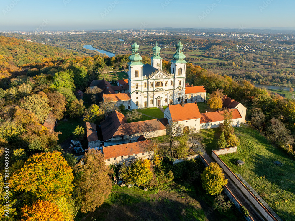 Active Camaldolese monastery and baroque church in a wood on the hill in Bielany, Krakow, Poland., Aerial view in sunset light in fall with Vistula River and far view of Cracow city in the background