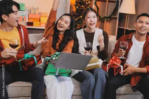 Group of young Asian man and women as friends having fun at a New Year's celebration, holding gift boxes standing by Christmas tree decoration, midnight countdown Party at home with holiday season.