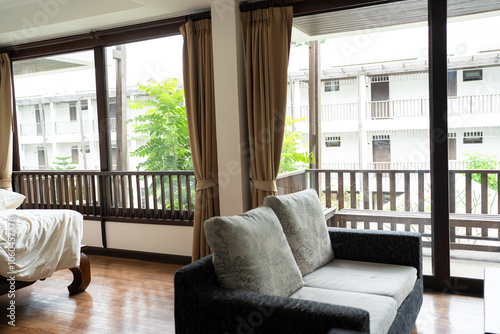 Modern gray toned sofa bed in hotel room with curtain and carpet decorate in earth tone photo