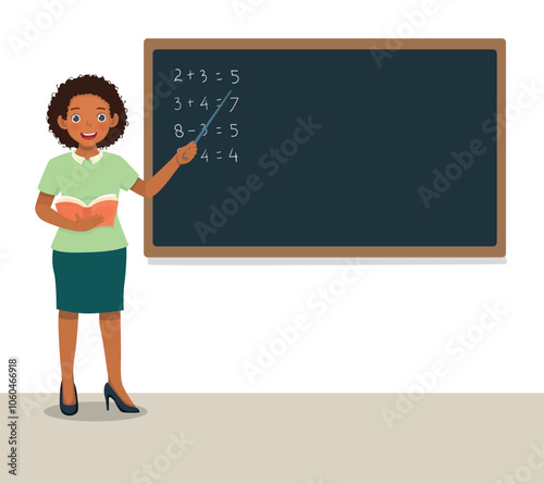 Young female African teacher standing in front of class teaching math lesson at blackboard
