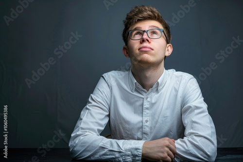 A thoughtful man wearing glasses and a white shirt, looking contemplatively to the side. Modern portrait.