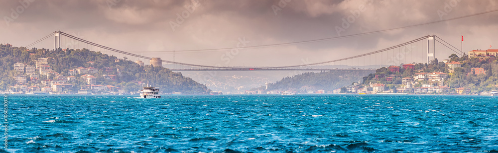 Fototapeta premium A panoramic view of the Bosphorus in Istanbul, where the serene blue waters meet the horizon, with a bridge and boats dotting the landscape