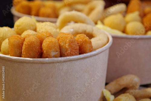 Fried potatoes, cheese fried balls and other baked goods in large paper bowls photo