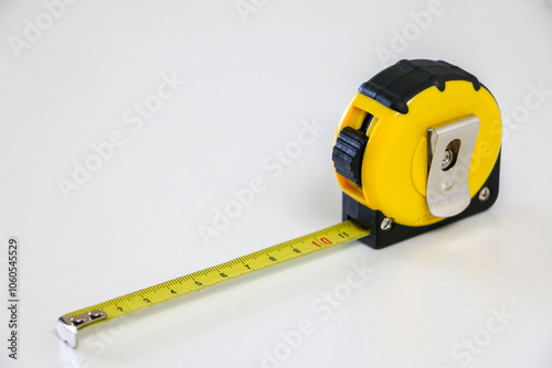 Black and yellow retractable tape measure held in place at 10 cm, on white background, useful tool for measuring length, width and height. Accuracy and precision concept photo