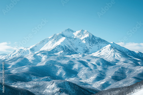 Snow-covered mountains reach towards a clear blue sky under bright sunlight in a serene winter landscape