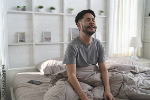 Portrait of tired funny slumber man after awakening on his bed in bedroom at home. Don't want to wake up concept