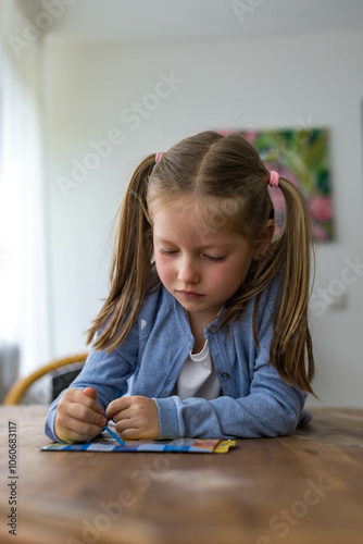 A 5-year-old girl smiles brightly as she draws, showcasing her creativity and joy in art