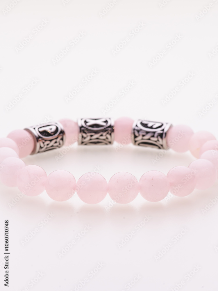 A charming double bracelet in shades of pink, made from natural stone and set against a gray background. The heart charm with cubic zirconia stands out in this close-up top view A charming double bracelet in shades of pink, made from natural stone and set against a gray background. The heart charm with cubic zirconia stands out in this close-up top view