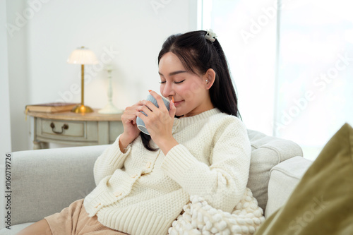 Young asian woman enjoying having coffee in living room at home