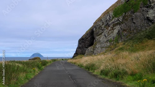 Disused road by Irish Sea in Scotland, Ailsa island on horizon, Snib's Cave seen on the right. photo