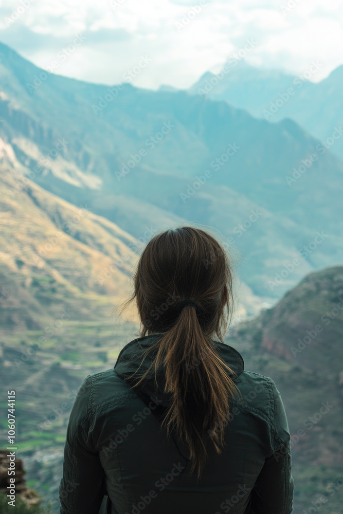 Naklejka premium Woman standing at high vantage point in Andes, gazing over valley and mountains, appreciating natural beauty.