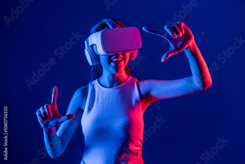 Female stand surrounded by neon light wear VR headset connecting metaverse, futuristic cyberspace community technology, spread both hand index and thumb finger interact virtual object. Hallucination. photo