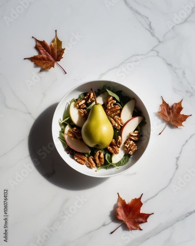 fresh pear and walnut salad with autumn leaves on white marble background.
