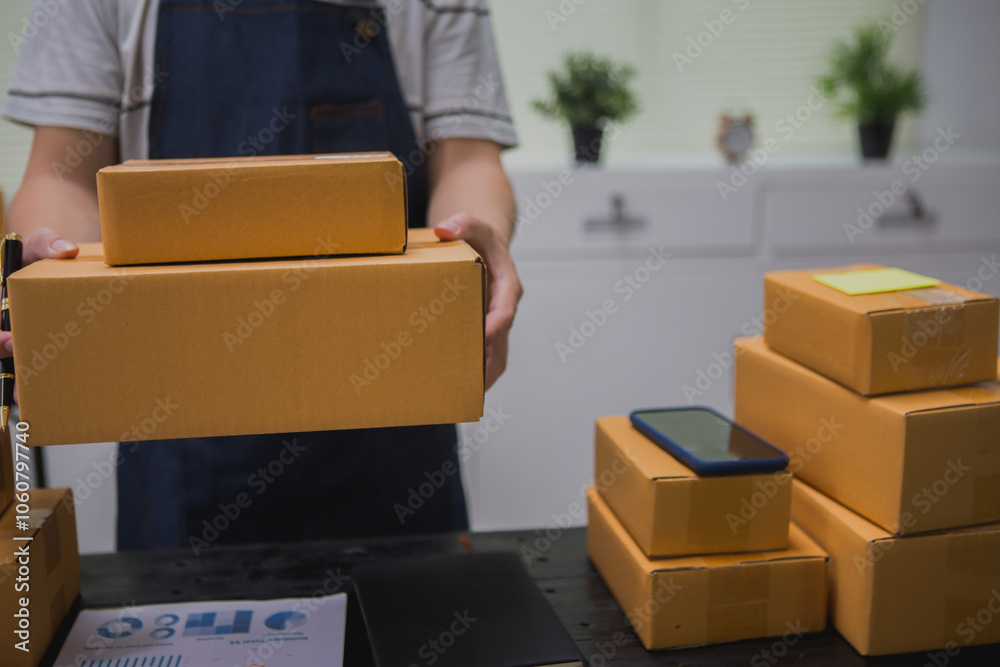 An Asian man carefully prepares a package for a customer's online order, methodically placing items in a box, sealing it securely, and attaching a shipping label for prompt delivery. An Asian man carefully prepares a package for a customer's online order, methodically placing items in a box, sealing it securely, and attaching a shipping label for prompt delivery.