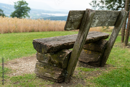 Rustic bench at a viewpoint with meadows, trees and a corn field. Lake in the distance. photo