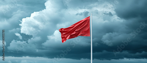 Red flag waving in stormy coastal area, signaling caution and danger