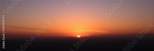 Vibrant hues of orange and purple in the sky as the sun sets over the horizon, casting a warm glow on the landscape below, evening, sun