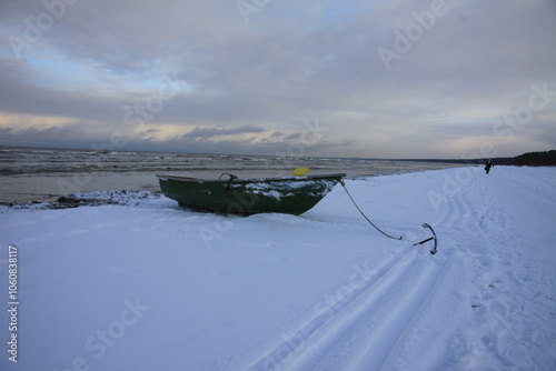 Winter landscape from the seashore,.  Fisherman boat on the seashore,  ice texture in Winter. 