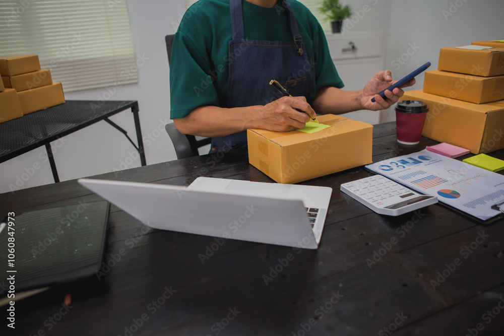 An Asian man carefully prepares a package for a customer's online order, methodically placing items in a box, sealing it securely, and attaching a shipping label for prompt delivery. An Asian man carefully prepares a package for a customer's online order, methodically placing items in a box, sealing it securely, and attaching a shipping label for prompt delivery.