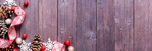 Christmas corner border of red and brown ribbon, snowflakes, baubles and pinecones. Above view on a dark wood banner background. Copy space.