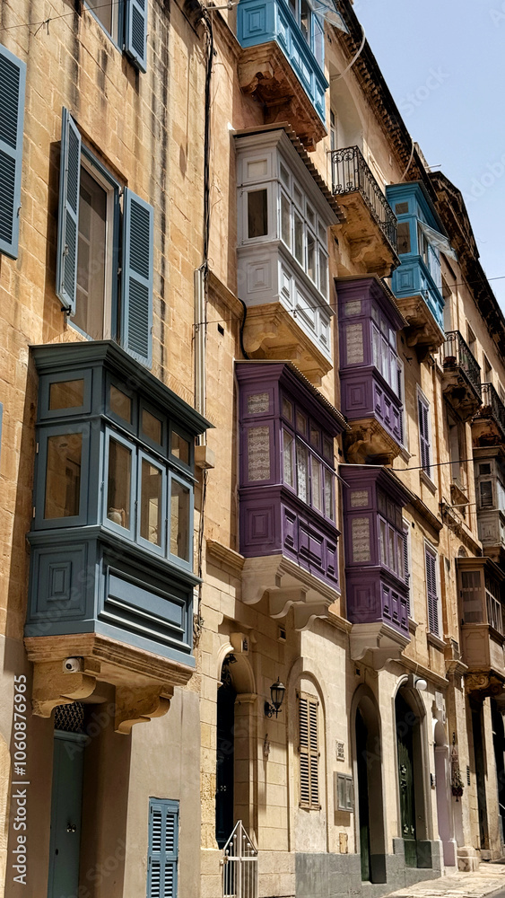 Fototapeta premium Typical narrow streets with colorful balconies in Malta. Traditional colorful balconies in old town of Valletta, Malta. Architecture background. Facade of the building in the old town, Malta island