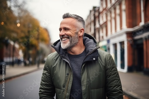 Handsome middle-aged man with grey hair and beard in a green jacket walking in the street