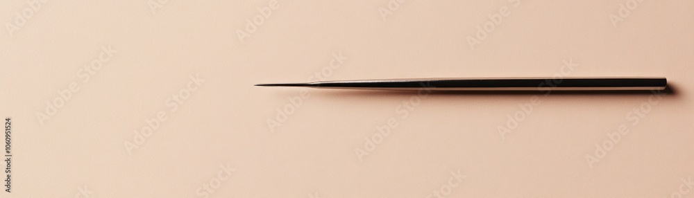 A Metallic Needle-like Tool on a Beige Surface A Metallic Needle-like Tool on a Beige Surface