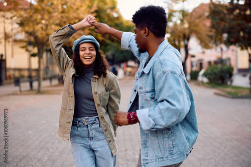 Young carefree couple dancing on street during autumn day.