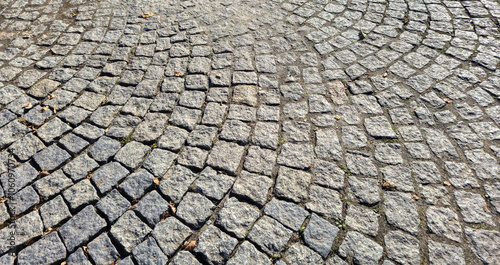 Textured cobblestone pavement in a circular pattern. Ideal for backgrounds in design projects or as a natural surface in urban photography.