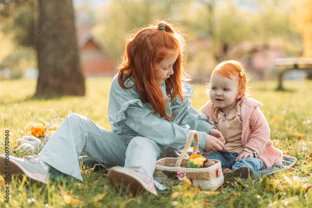 Two ginger, redhead little girls sitting outdoors in the park, playing Two ginger, redhead little girls sitting outdoors in the park, playing