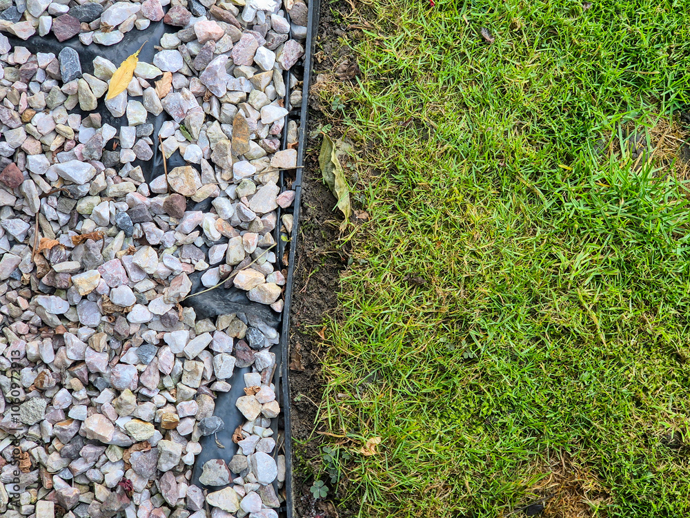 A close-up view of pebbles on one side and freshly mowed grass on the other, illustrating a beautiful transition between hardscape and landscape. Perfect for landscaping themes. A close-up view of pebbles on one side and freshly mowed grass on the other, illustrating a beautiful transition between hardscape and landscape. Perfect for landscaping themes.