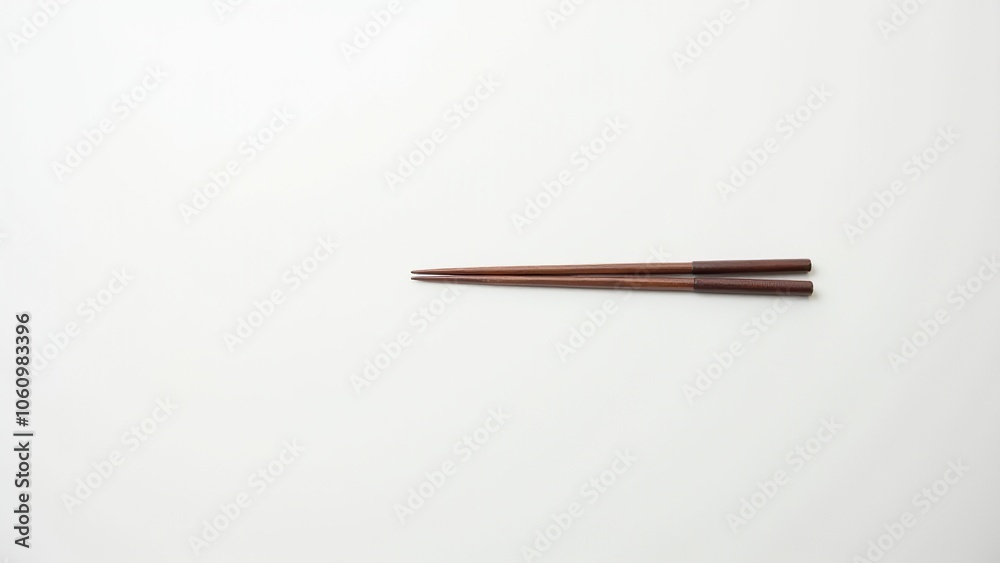 Pair of wooden chopsticks arranged on a white background, showcasing a minimalist style. Everyday things for dining. Pair of wooden chopsticks arranged on a white background, showcasing a minimalist style. Everyday things for dining.