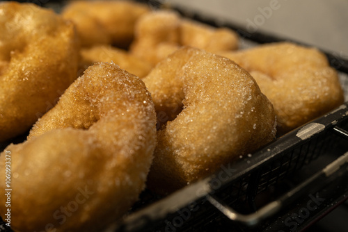 Golden doughnuts sprinkled with sugar cooling on a wire rack. These freshly fried doughnuts are soft on the inside and crisp on the outside, perfect for festive or holiday gatherings. photo