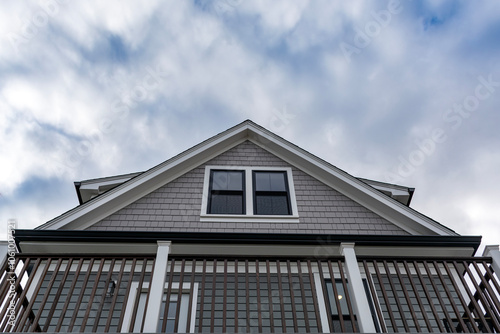 Upper facade of a house with attic window and balcony railing in Brighton, Massachusetts, USA