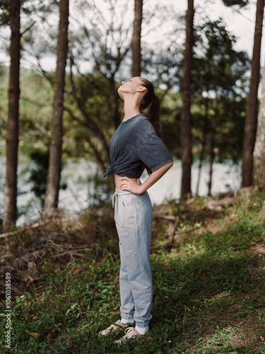 Young woman standing in nature, with head tilted back, enjoying the fresh air while wearing casual sportswear Serenity and freedom concept
