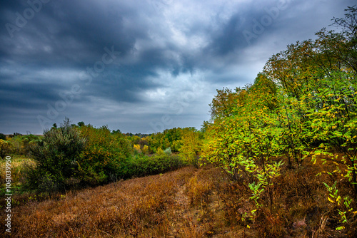 Landscape photography on the field with big and smooth clouds in the sky,Stormy weather on the picture.Big blue clouds iver the forest nd field, morning landscape in the woodlands.Aurumn blue hour,