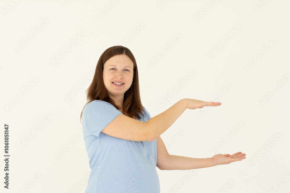 Young confident woman showing logo on empty space between arms. Smiling girl inviting or advertising promo deal, pointing hands right and looking at camera, white background. Young confident woman showing logo on empty space between arms. Smiling girl inviting or advertising promo deal, pointing hands right and looking at camera, white background.