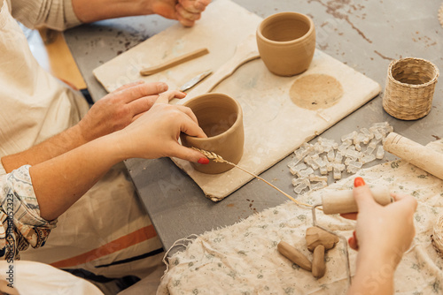 Cropped shot of unrecognizable child making ceramic mug at pottery class photo