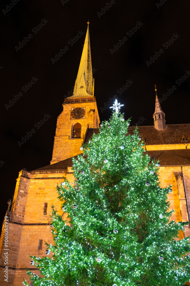 A festive scene with Christmas decorations in the foreground and the Cathedral of St. Bartholomew in Plzen, Czech Republic, in the background. A charming mix of tradition and holiday spirit