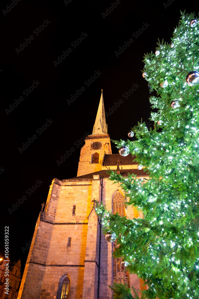 A festive scene with Christmas decorations in the foreground and the Cathedral of St. Bartholomew in Plzen, Czech Republic, in the background. A charming mix of tradition and holiday spirit