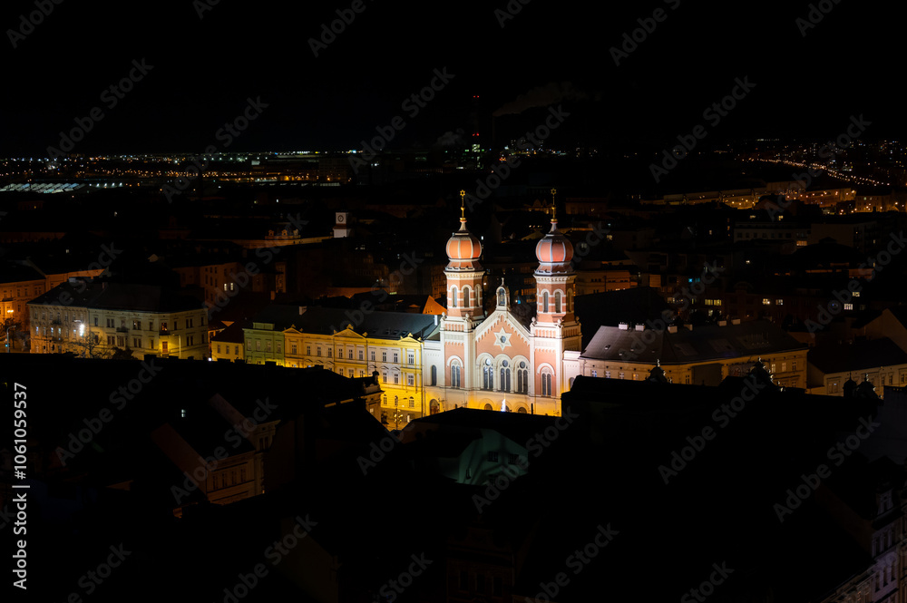A captivating night view of the illuminated synagogue in Pilsen, showcasing its stunning architecture and warm lights, creating a serene and magical atmosphere