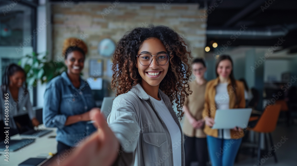 young female executive extends her hand to greet a partner in her office.