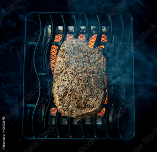 Top down view of a seasoned top sirloin steak cooking on an red hot infrared sear box on a grill