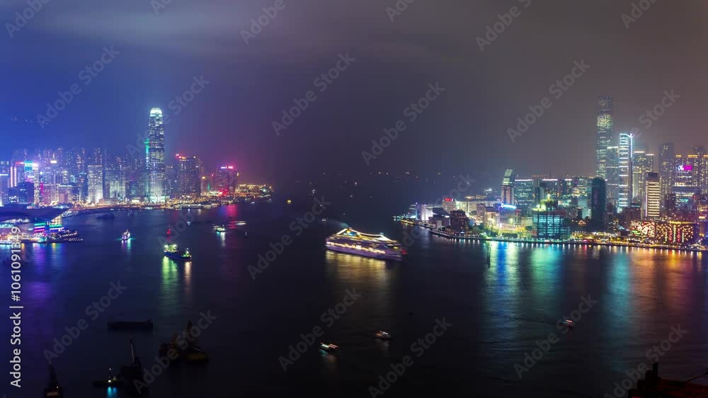 HONG KONG, - OCTOBER 27, 2024: HK ship sails through brightly lit harbor under a night sky with stunning city skyline views
