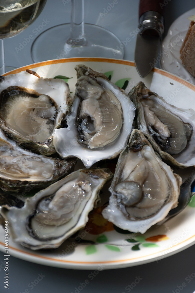 Plate with fresh live oysters with citron, bread, butter and white wine served at restaurant in oyster-farming village, Arcachon bay, Gujan-Mestras port, France Plate with fresh live oysters with citron, bread, butter and white wine served at restaurant in oyster-farming village, Arcachon bay, Gujan-Mestras port, France