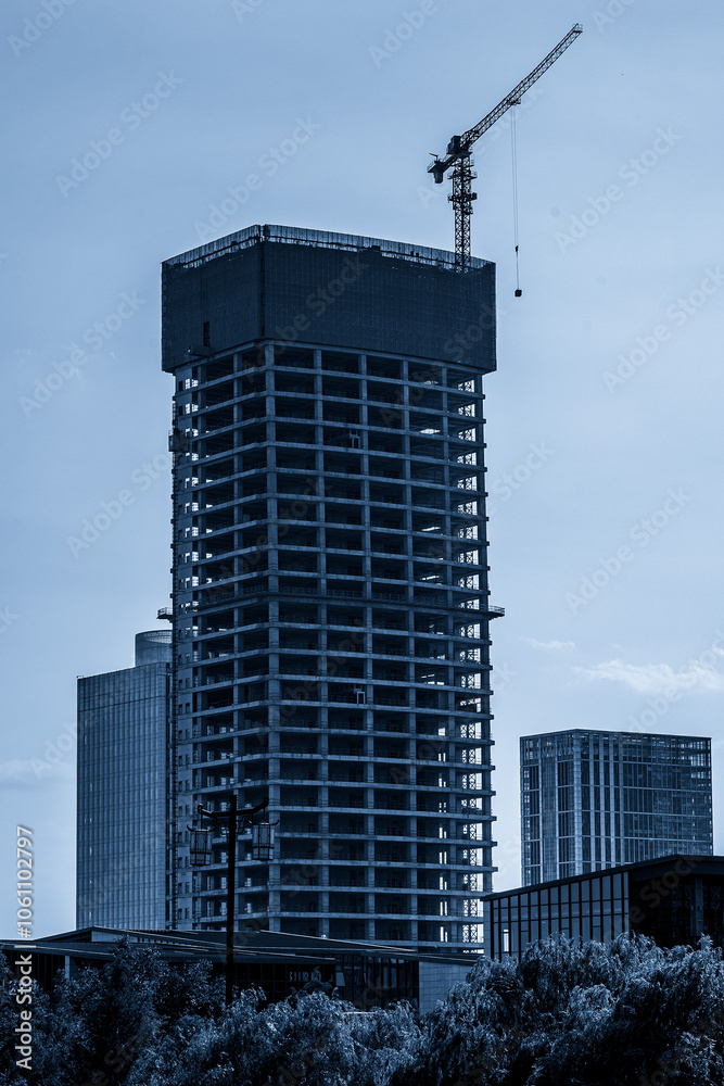 Modern Skyscraper Under Construction with Crane and Urban Landscape Modern Skyscraper Under Construction with Crane and Urban Landscape