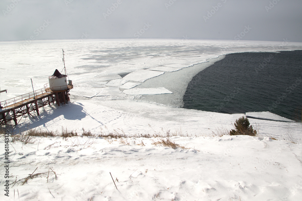 The ice-free Angara River flows out of the frozen Lake Baikal. Melted ice floes on blue water. Located Baikal lake. The ice-free Angara River flows out of the frozen Lake Baikal. Melted ice floes on blue water. Located Baikal lake.