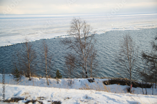 The ice-free Angara River flows out of the frozen Lake Baikal. Melted ice floes on blue water.  Located Baikal lake. photo