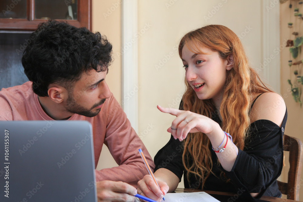 young couple sitting at the table and using laptop working and studying at home young couple sitting at the table and using laptop working and studying at home
